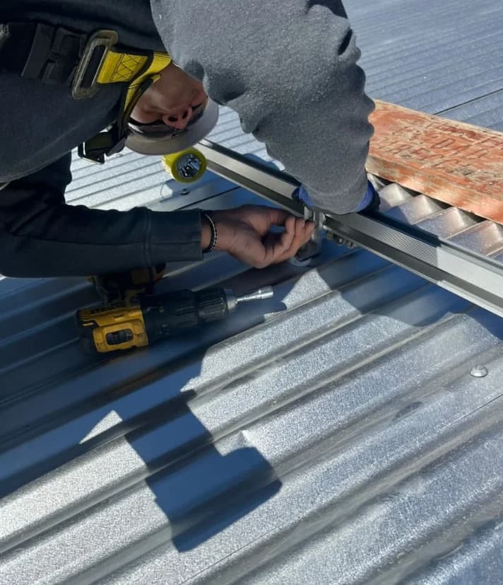 Técnico fijando rieles de montaje sobre cubierta metálica