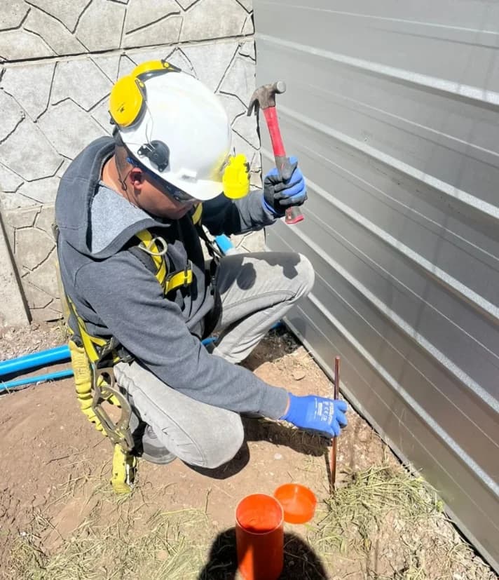 Técnico con casco, arnés y protección auditiva ejecutando puesta a tierra